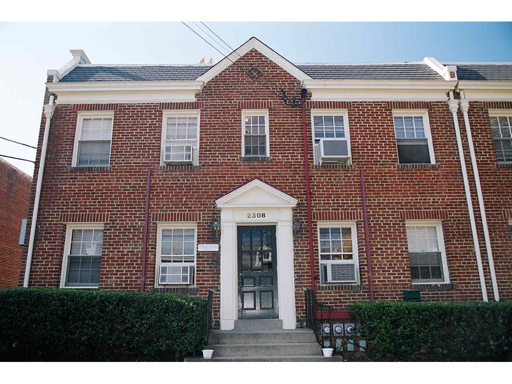 the front of a red brick house with a blue door